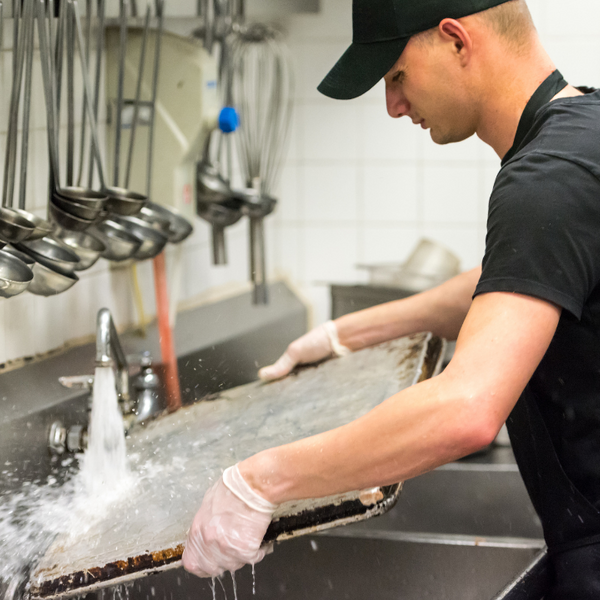 Person in a black t-shirt rinsing offa  sheet pan
