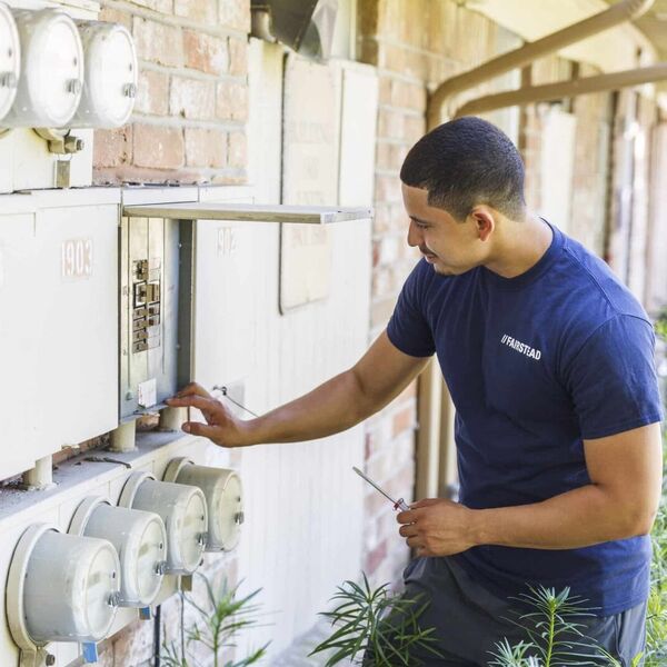 Person in blue Fairstead shirt checking utility box