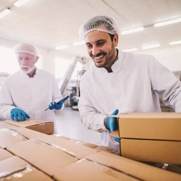 Person in white coat with hair net holding two pacakges